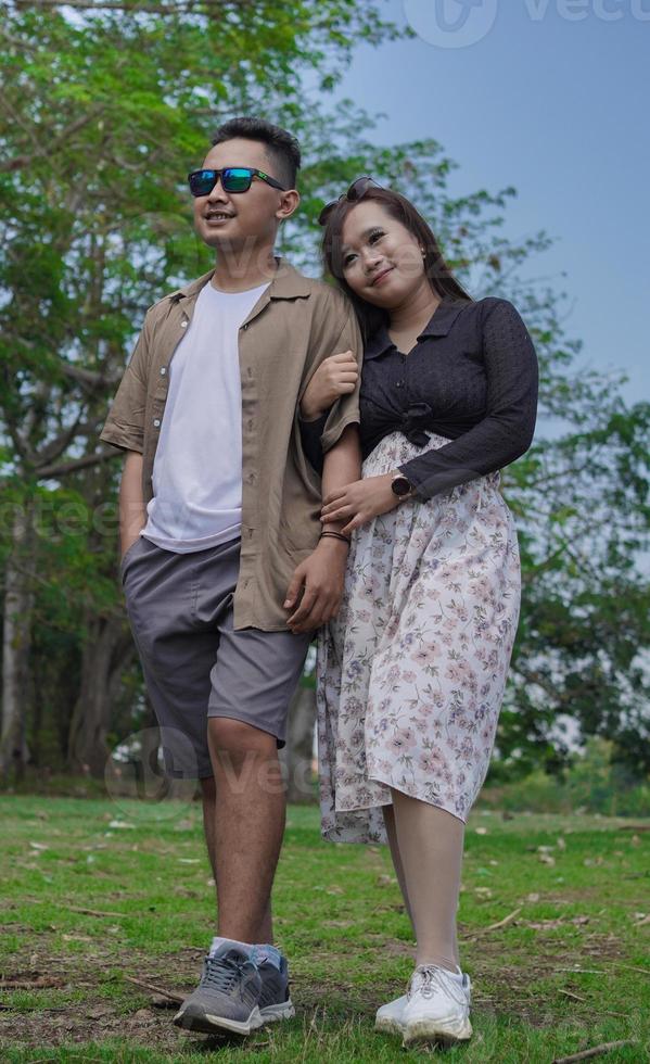 young couple holding hands and walking together in the park photo