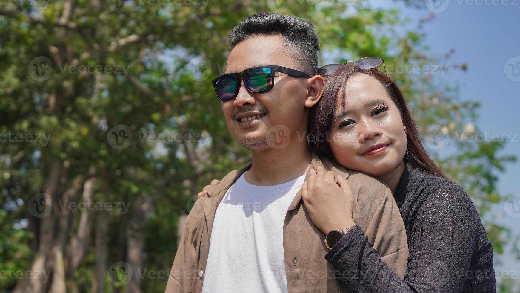 feliz pareja joven apoyándose unos a otros en el parque de primavera foto