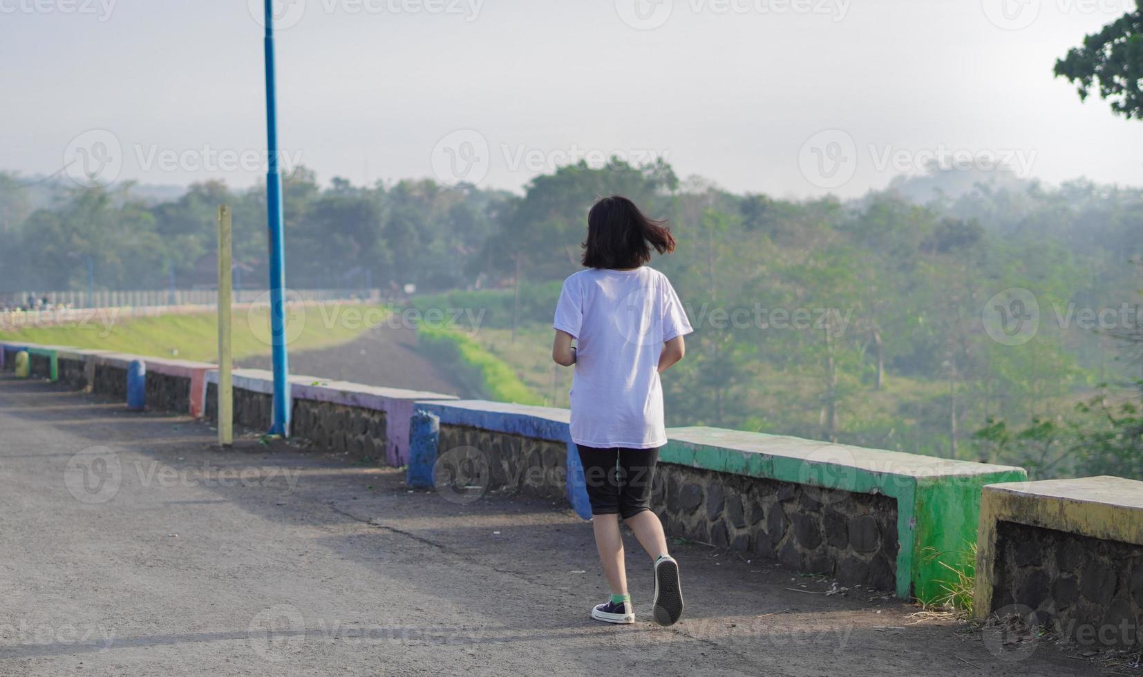 joven mujer asiática fitness está corriendo y trotando un entrenamiento al aire libre en la carretera por la mañana foto