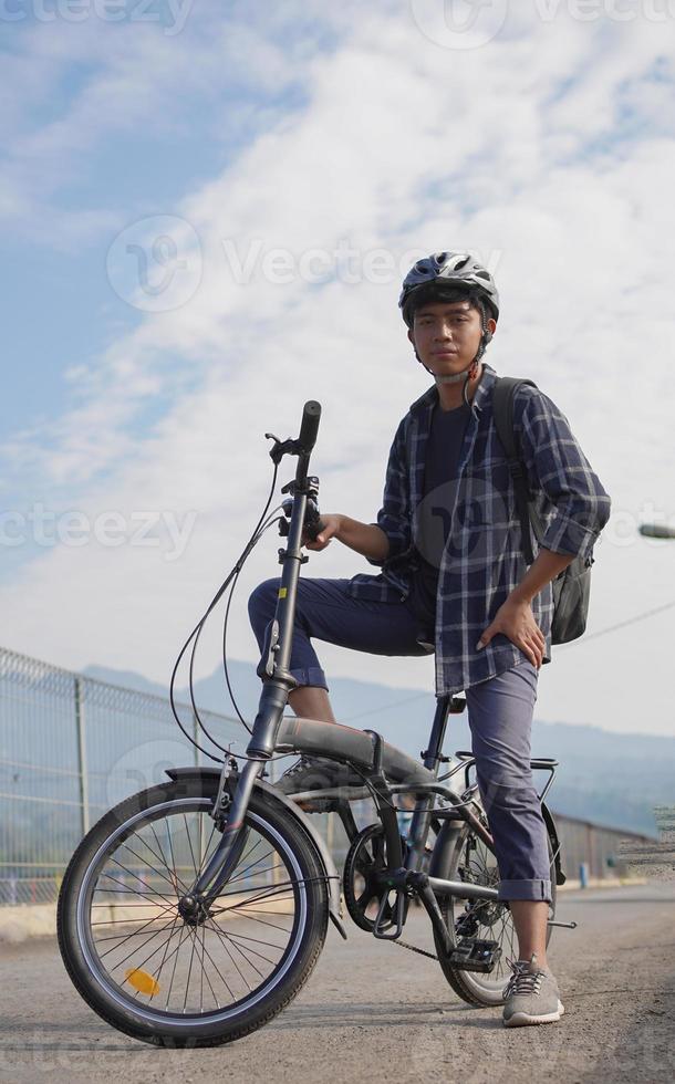 asian young man with backpack having rest after ride bicycle photo