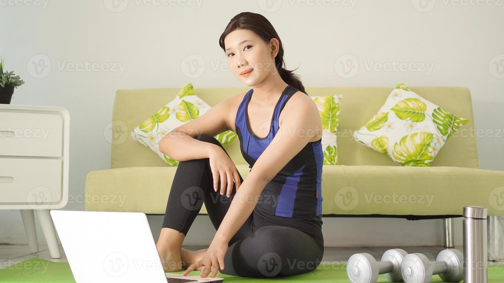 young woman finishes yoga practice looking at laptop screen photo