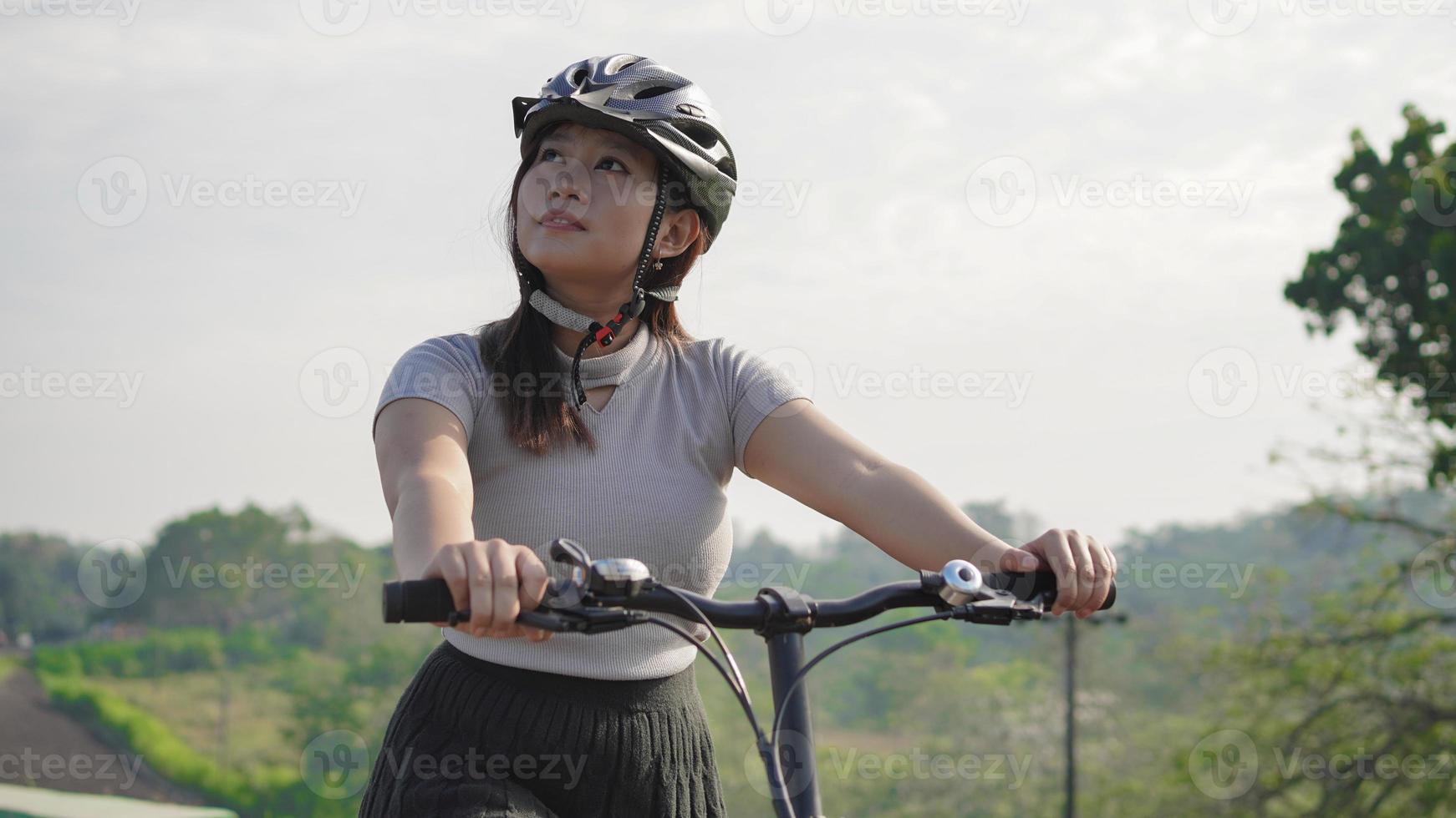 joven asiática disfrutando del ciclismo y el paisaje en la mañana de verano foto
