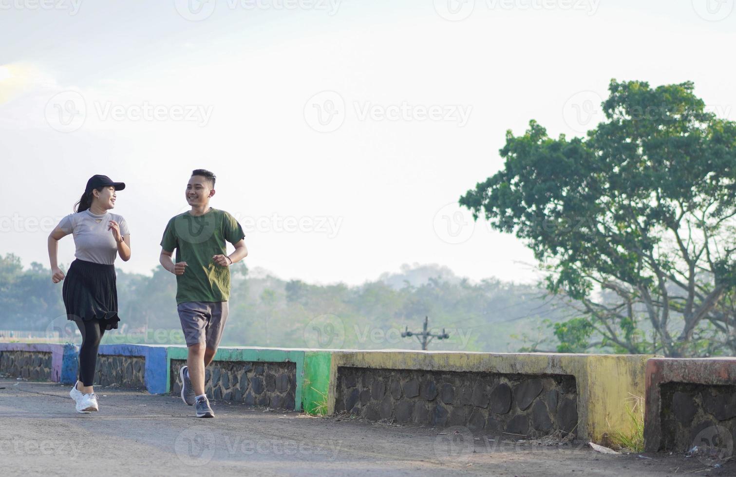 young asian couple in sporty clothes running together in the morning photo