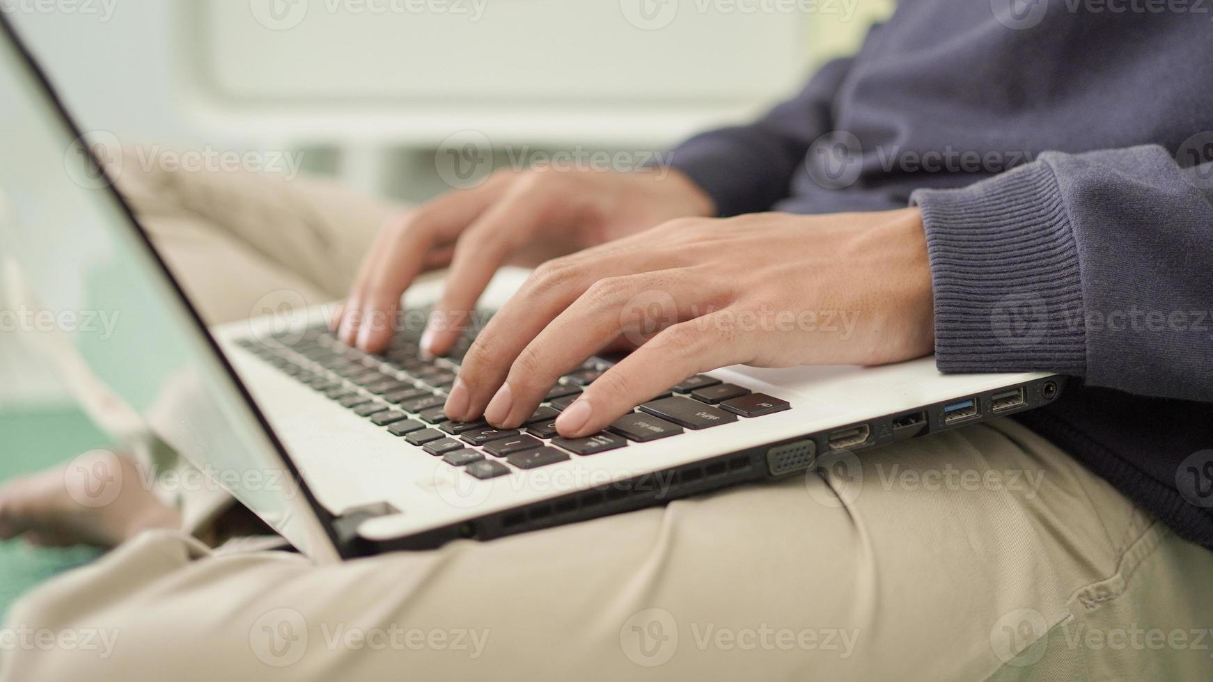 handsome asian man typing laptop at home photo