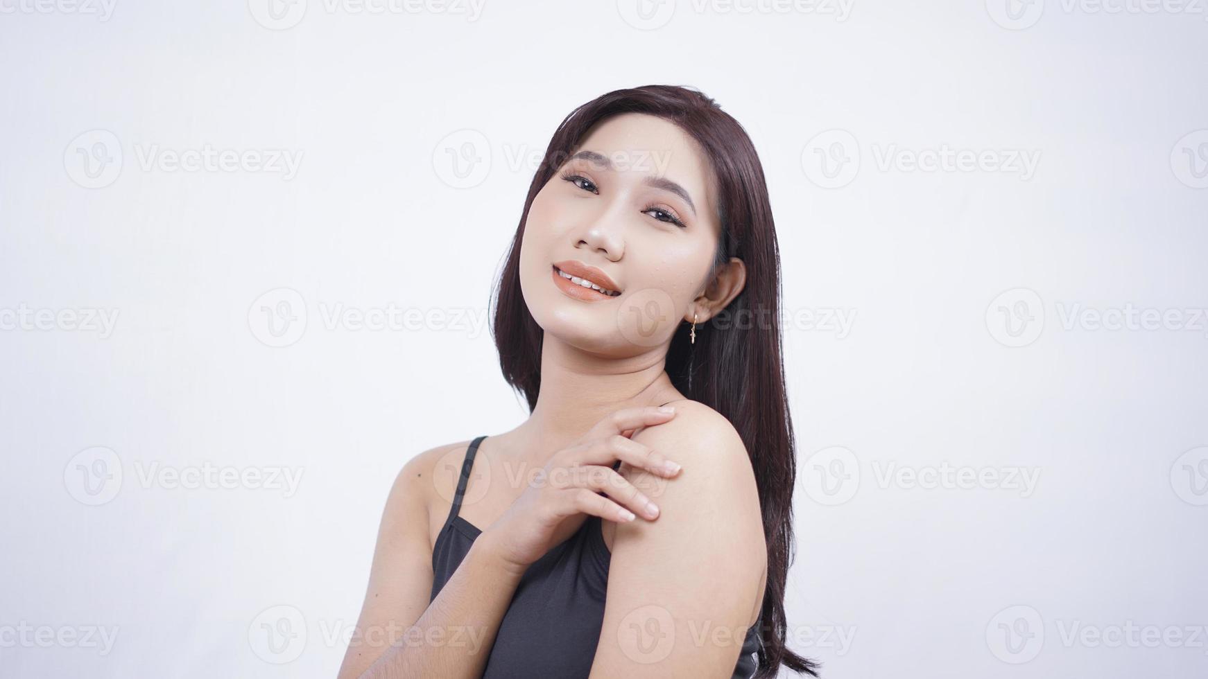 La belleza asiática muestra su maquillaje desde el lado aislado de fondo blanco foto