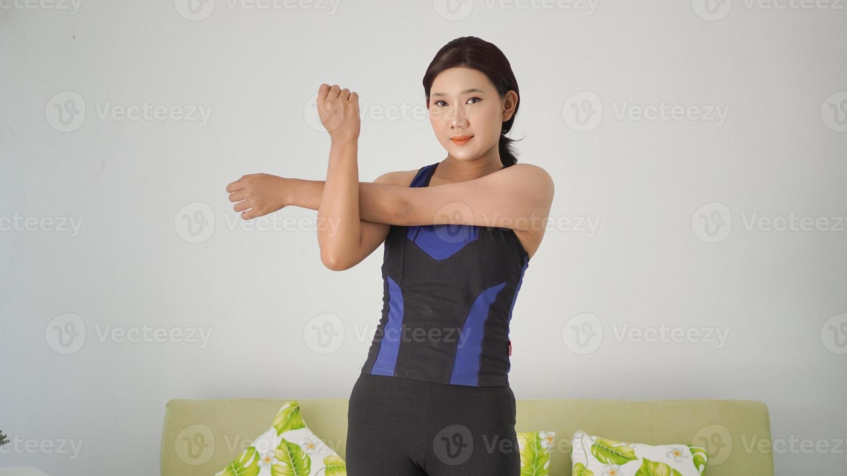 asian woman practicing yoga at home warming up hand gesture photo