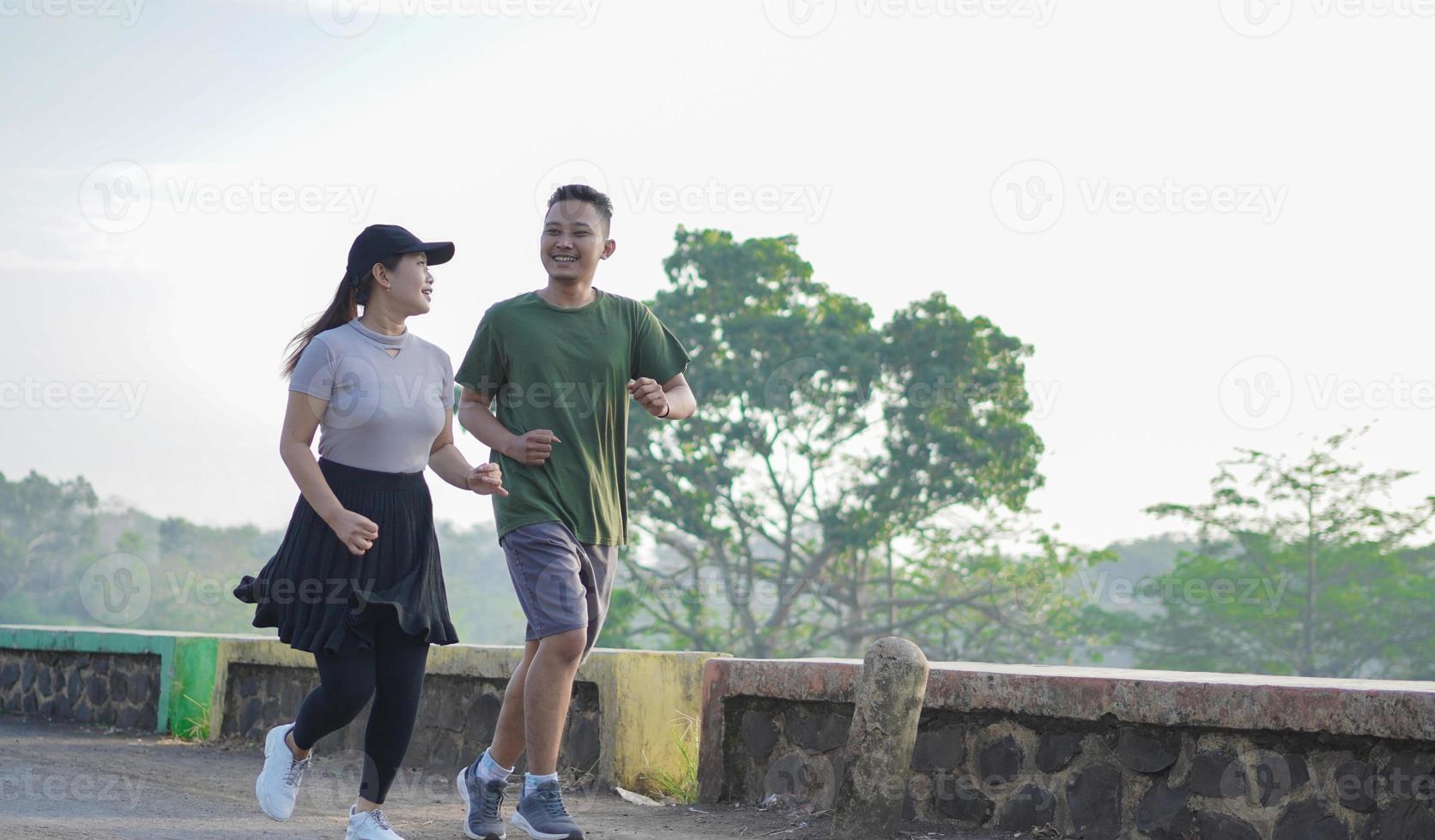 young asian couple in sporty clothes running together in the morning photo