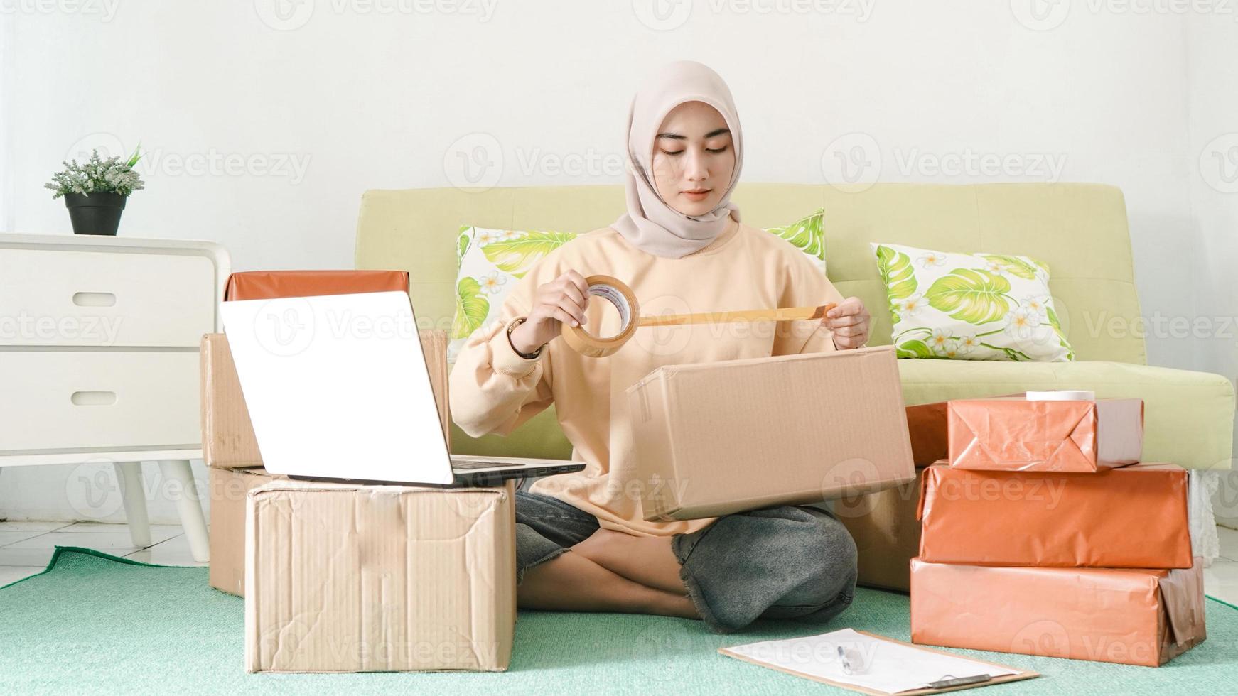 hermosa mujer de negocios asiática empacando pedidos de clientes en su habitación foto