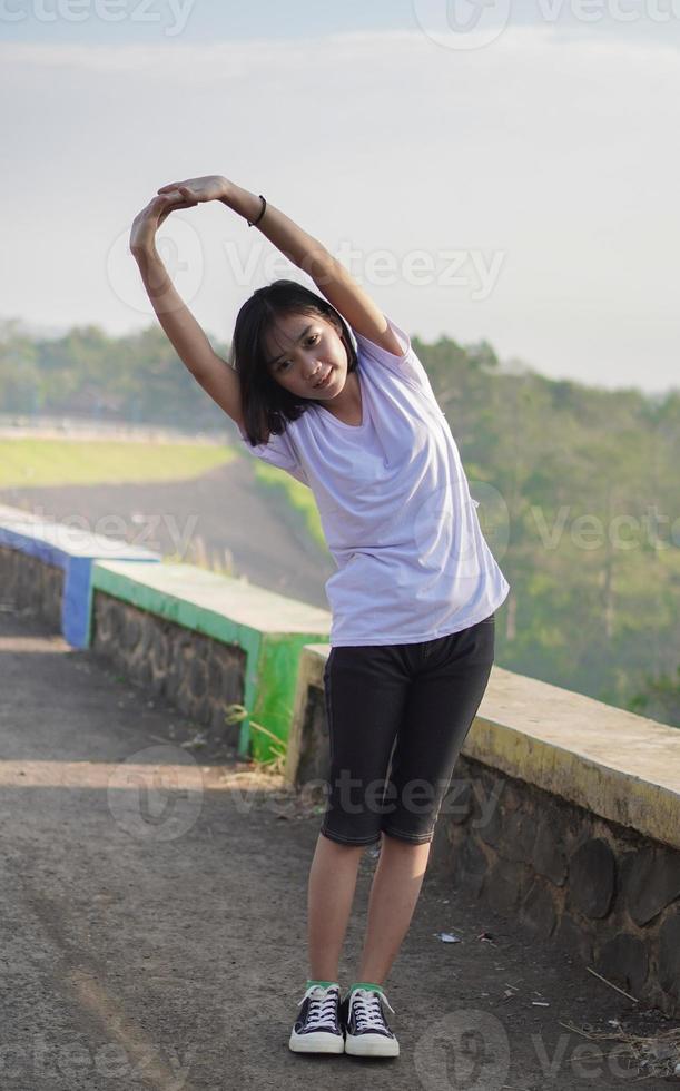 una joven asiática se estira antes de trotar y correr por la mañana foto