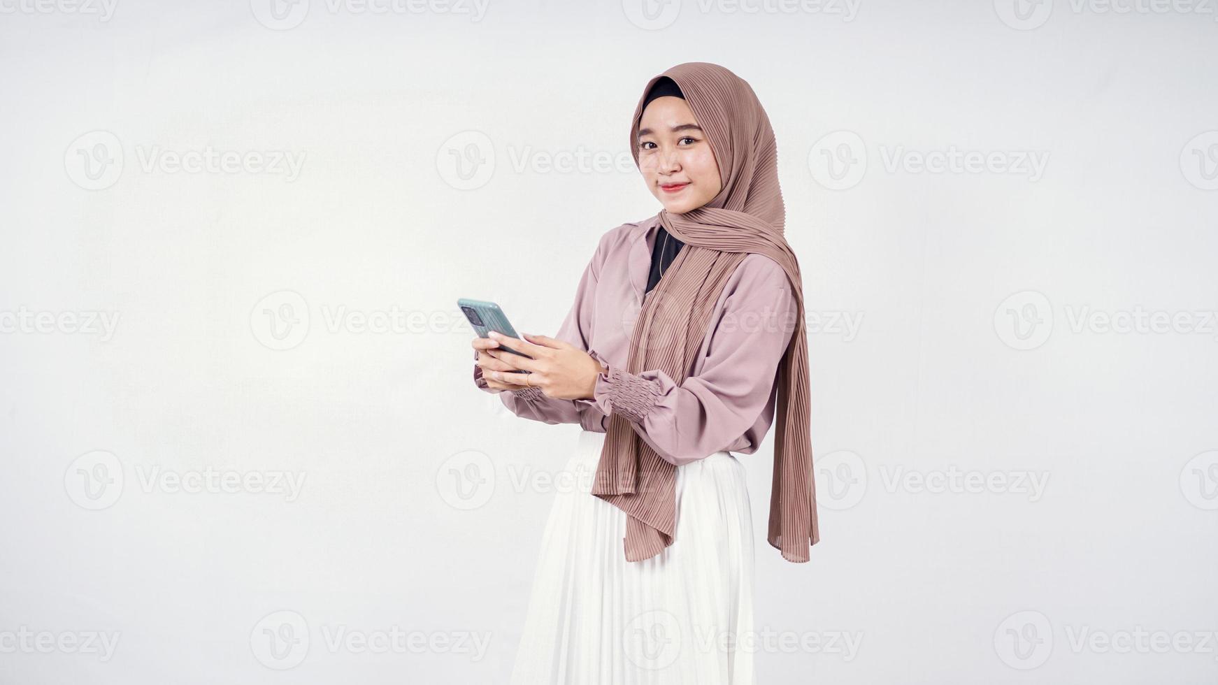 Hermosa mujer en hijab jugando smartphone disfrutando aislado sobre fondo blanco. foto