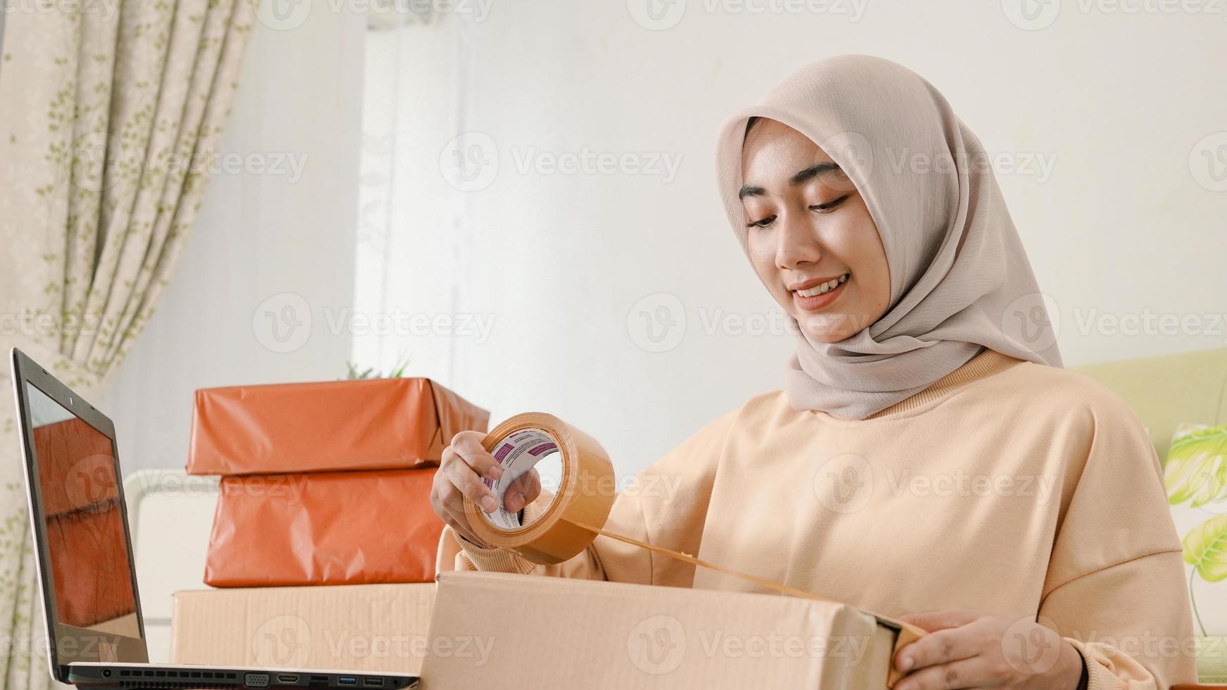 hermoso joven empresario asiático felizmente empacando pedidos de clientes foto