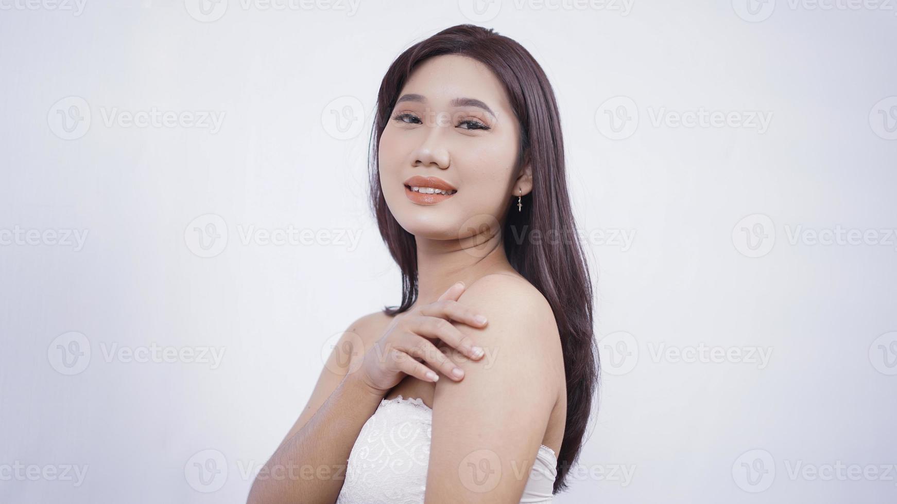 asian girl with make-up smiling sweetly hand sideways shoulder isolated on white background photo