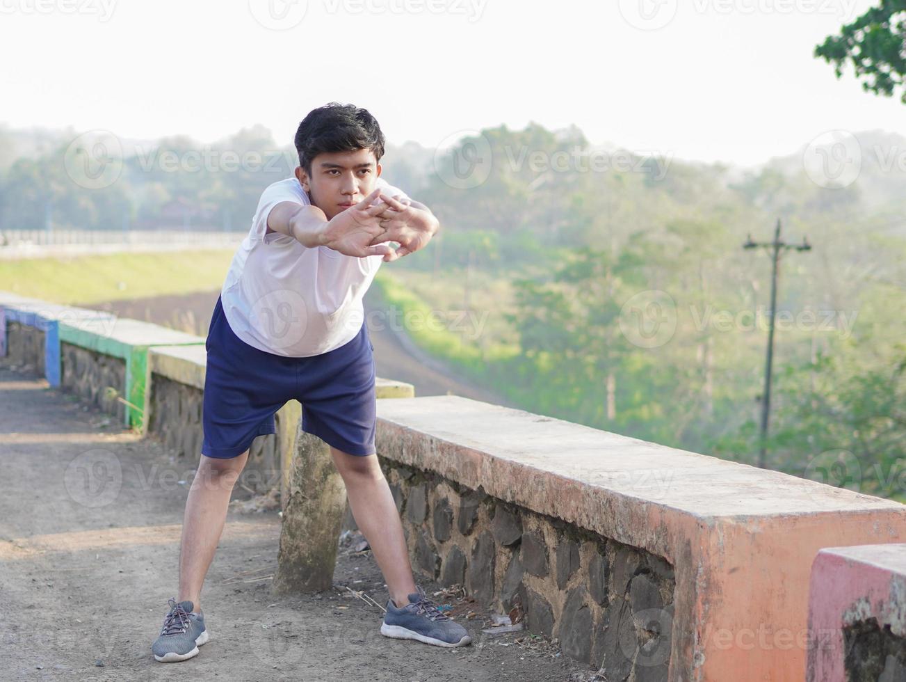 young asian man having streaching before jogging in the morning photo