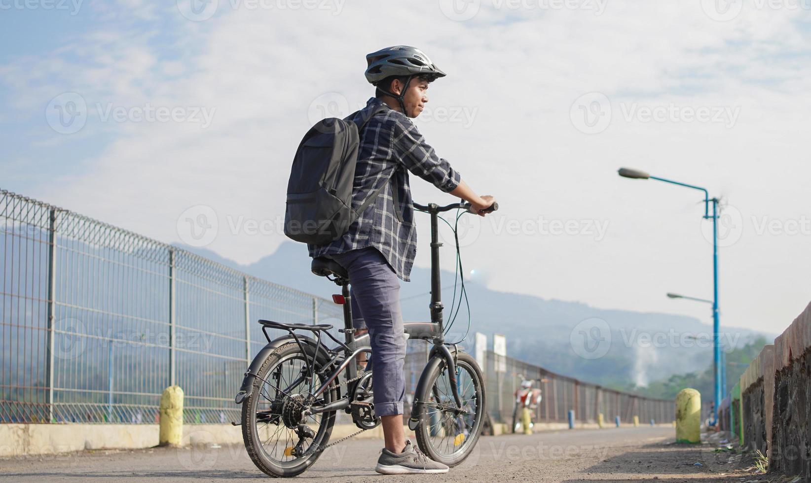 asian young man with backpack having rest after ride bicycle photo