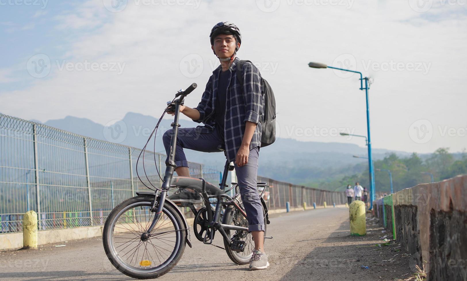 asian young man with backpack having rest after ride bicycle photo