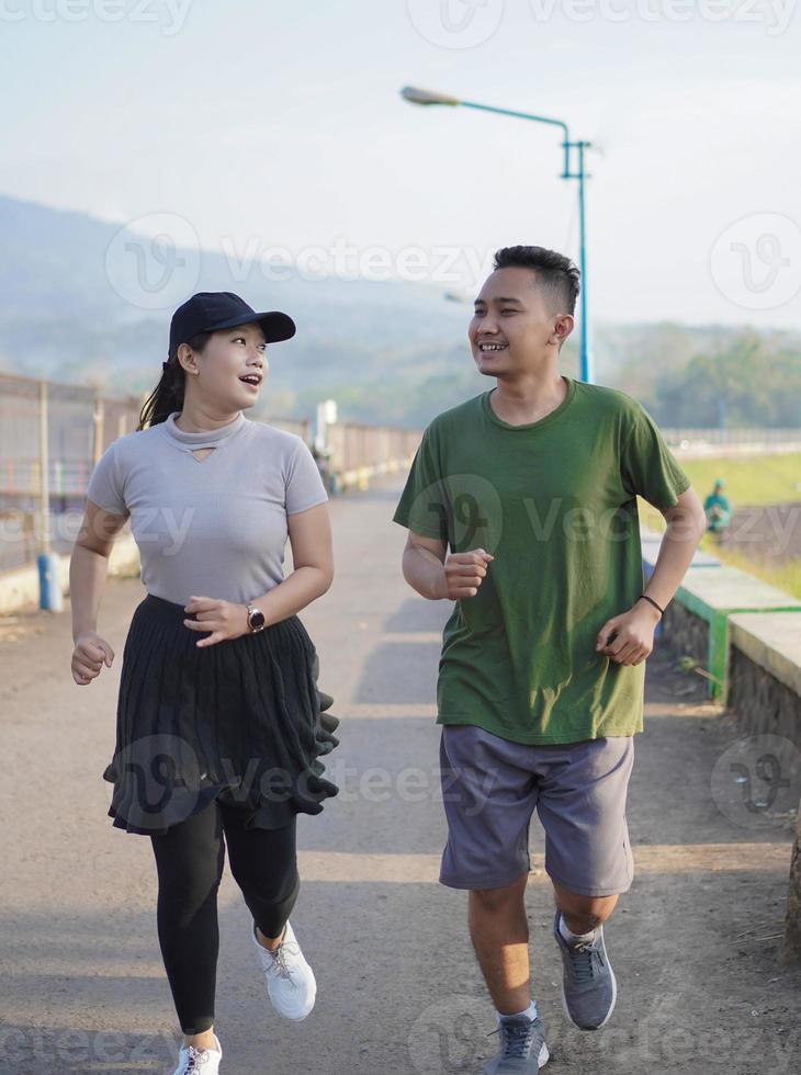 young asian couple in sporty clothes running together in the morning photo