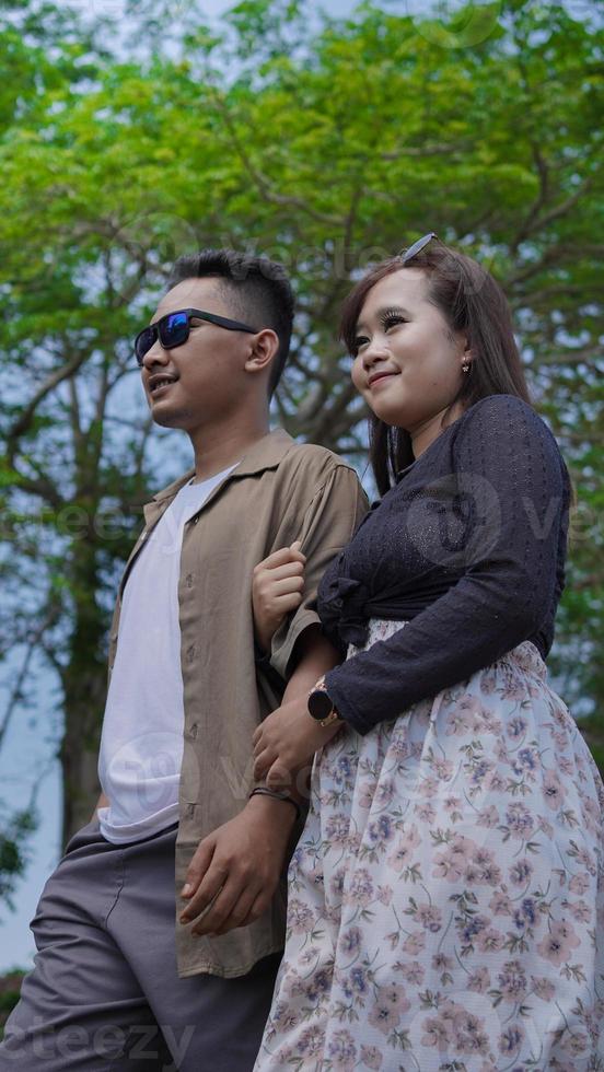 young couple holding hands and walking together in the park photo