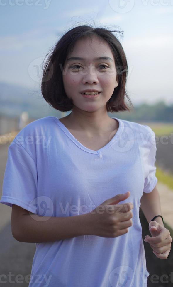Young Asian woman is running and jogging an outdoor workout on the road in the morning photo