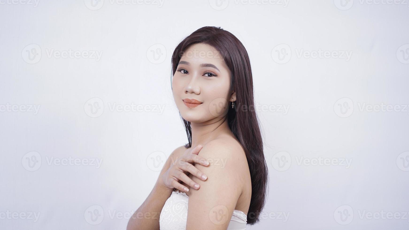 asian girl with make-up smiling sweetly hand sideways shoulder isolated on white background photo