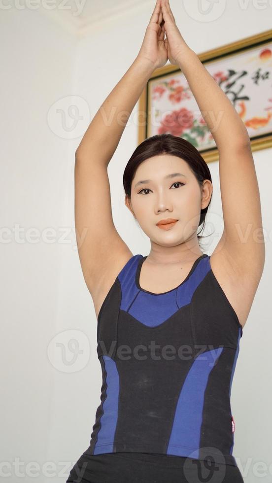 asian woman practicing yoga at home doing warm up hand movement photo
