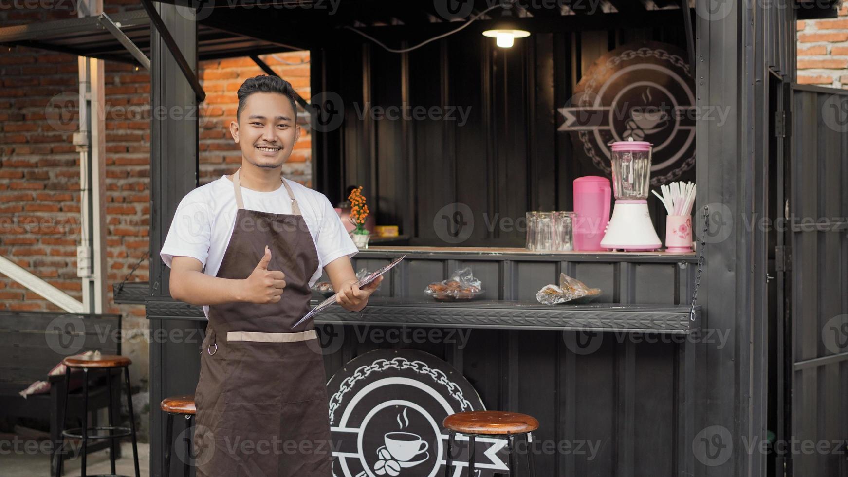 asian man in bar apron carrying a sign menu list ok in a container theme angkringan photo