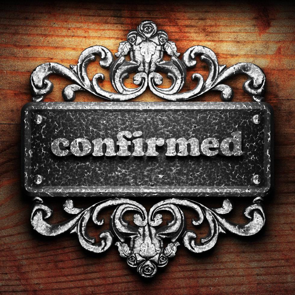 confirmed word of iron on wooden background photo