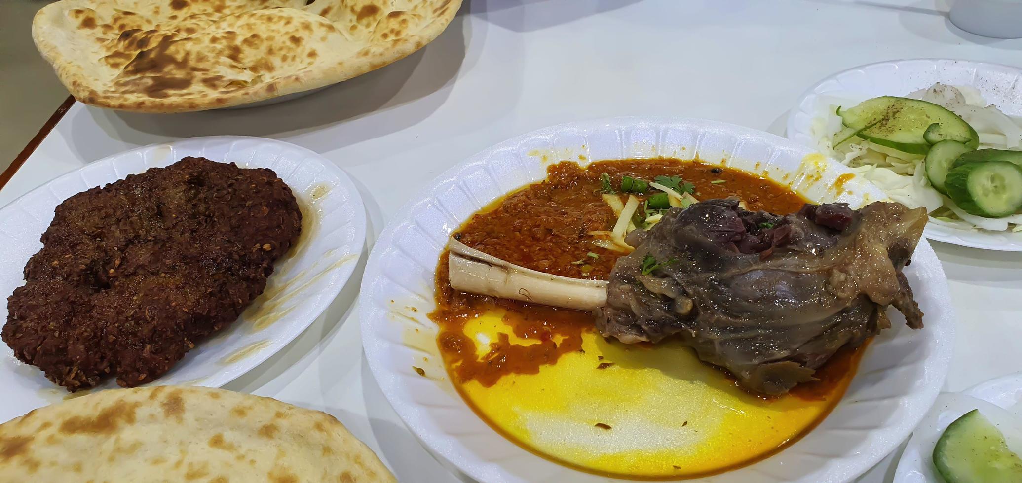 Camel meat in a plate and green coriander and green pepper on top with salads and bread selective focus, selective focus on subject, background blur photo