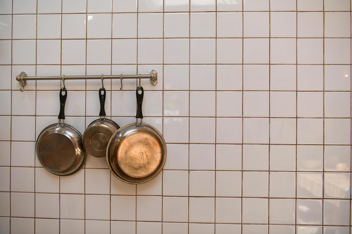 Cooking pan hanging on the kitchen wall after cleaning is complete. photo