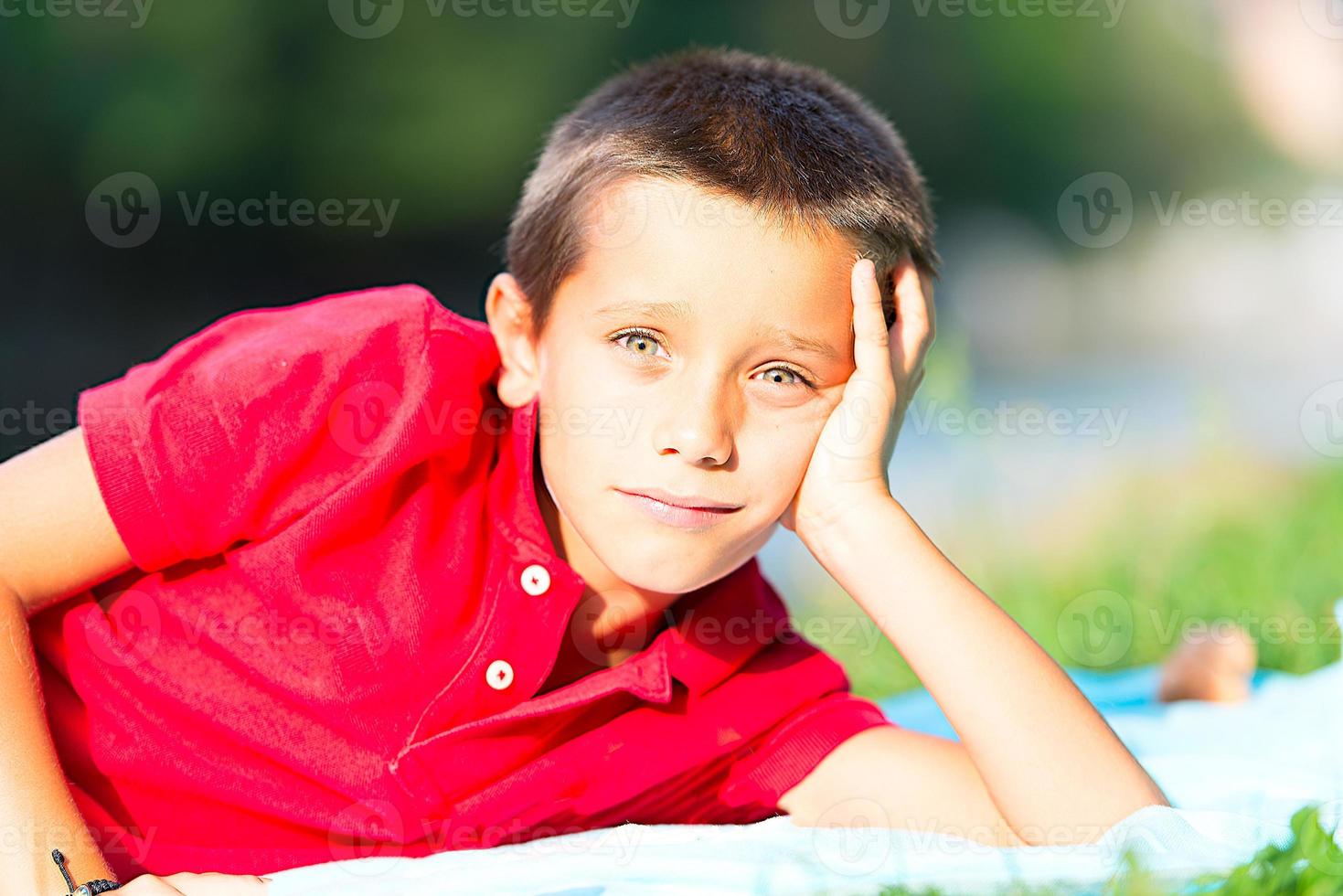 Little boy with a red mesh sitting in the meadow photo