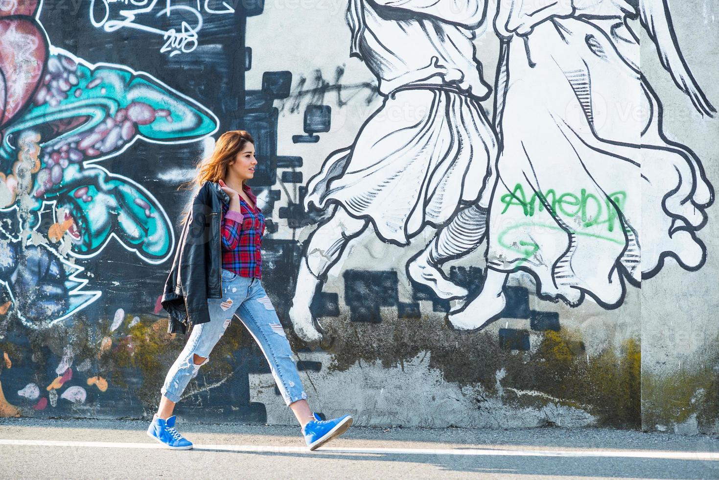 jovencita caminando a lo largo de una pared de graffiti foto