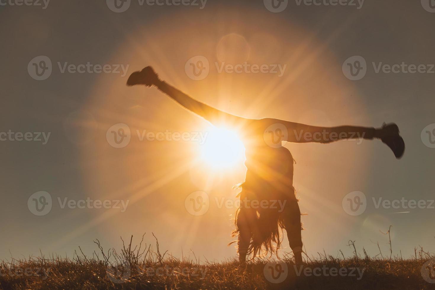 A little girl performs the wheel in a meadow photo