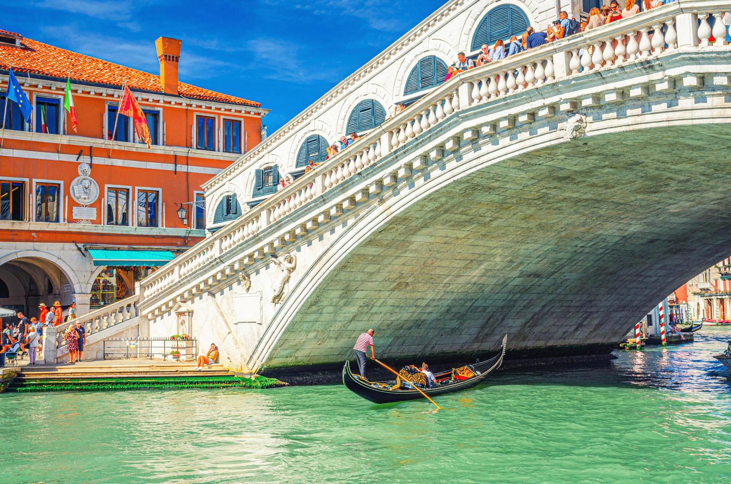 Venice, Italy, September 13, 2019 Gondolier and tourists on gondola traditional boat sailing on water of Grand Canal in Venice photo