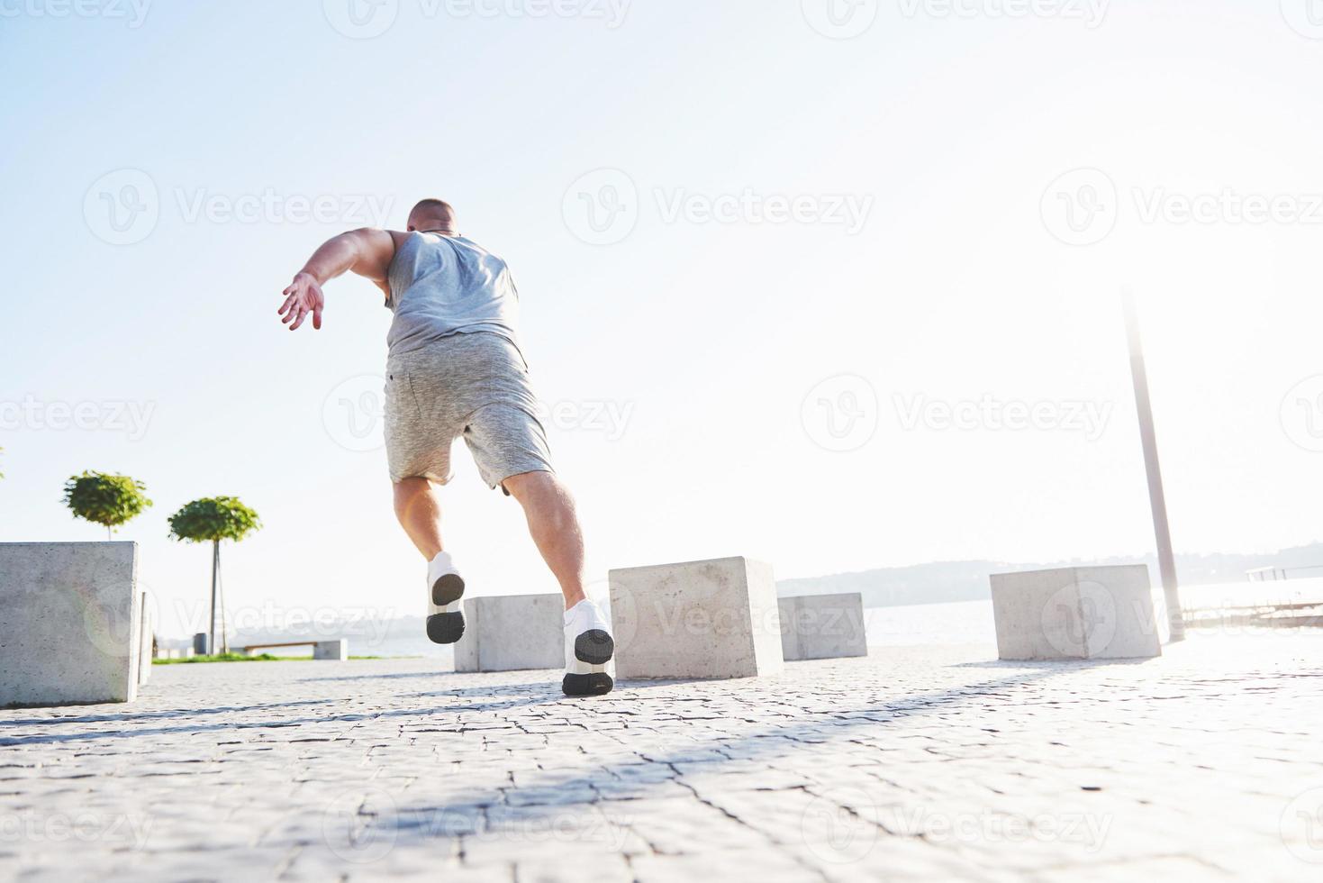 man runner doing stretching exercise, preparing for morning workout in the park photo