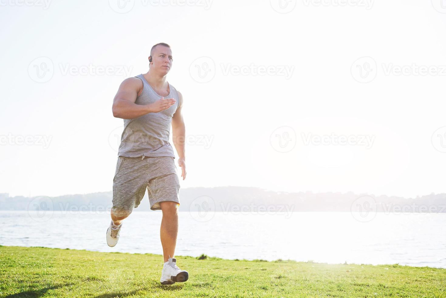 Fitness man athlete jogging in the nature during sunset. Person running working out living an active lifestyle training cardio in summer in sportswear and shoes. photo
