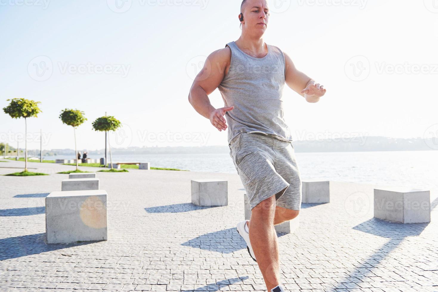 man runner doing stretching exercise, preparing for morning workout in the park photo