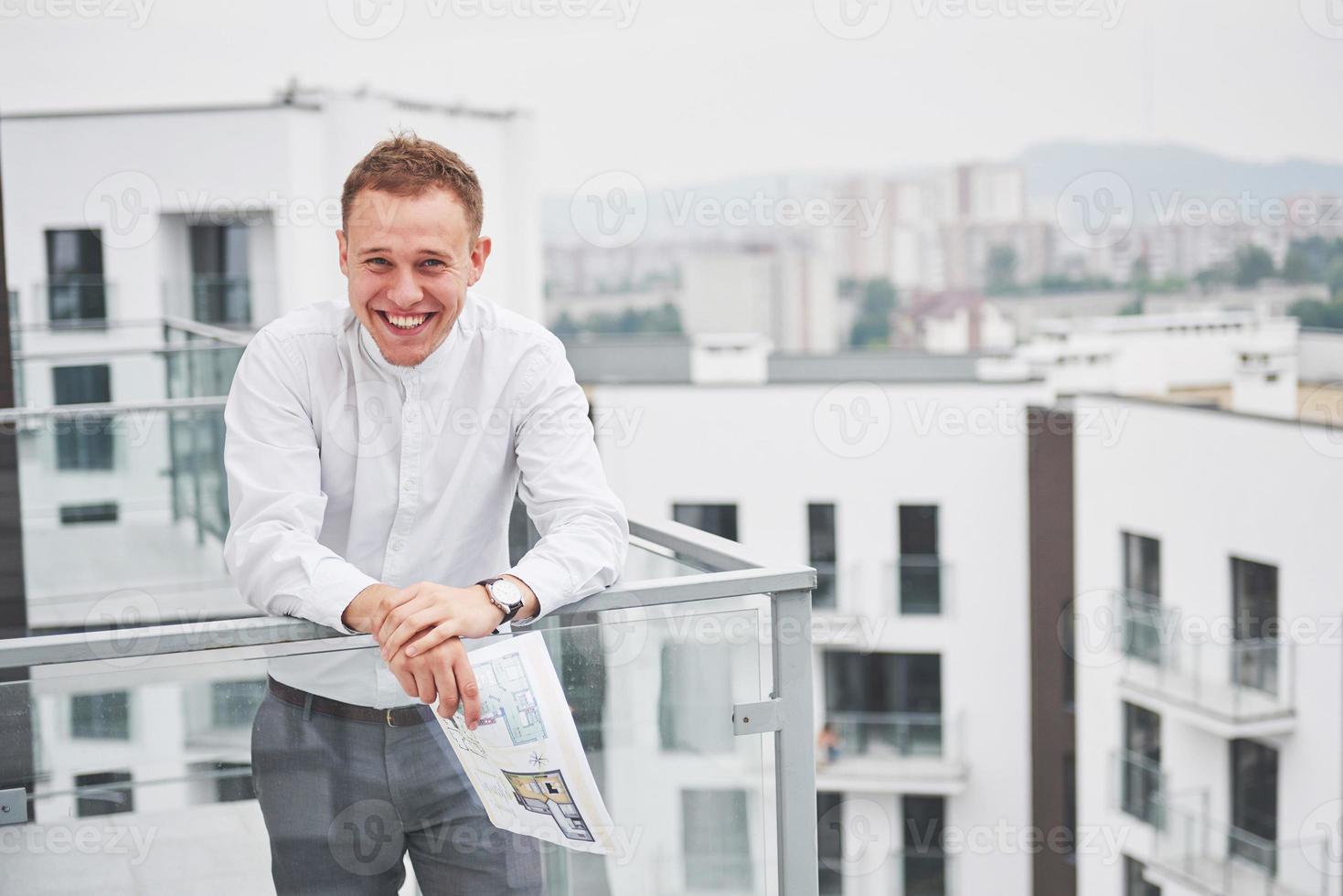 arquitecto joven sonriente o constructor de ingeniería con sombrero duro con tableta sobre un grupo de constructores en el sitio de construcción, arquitecto viendo algo de construcción, negocios, construcción, industria, concepto de personas foto