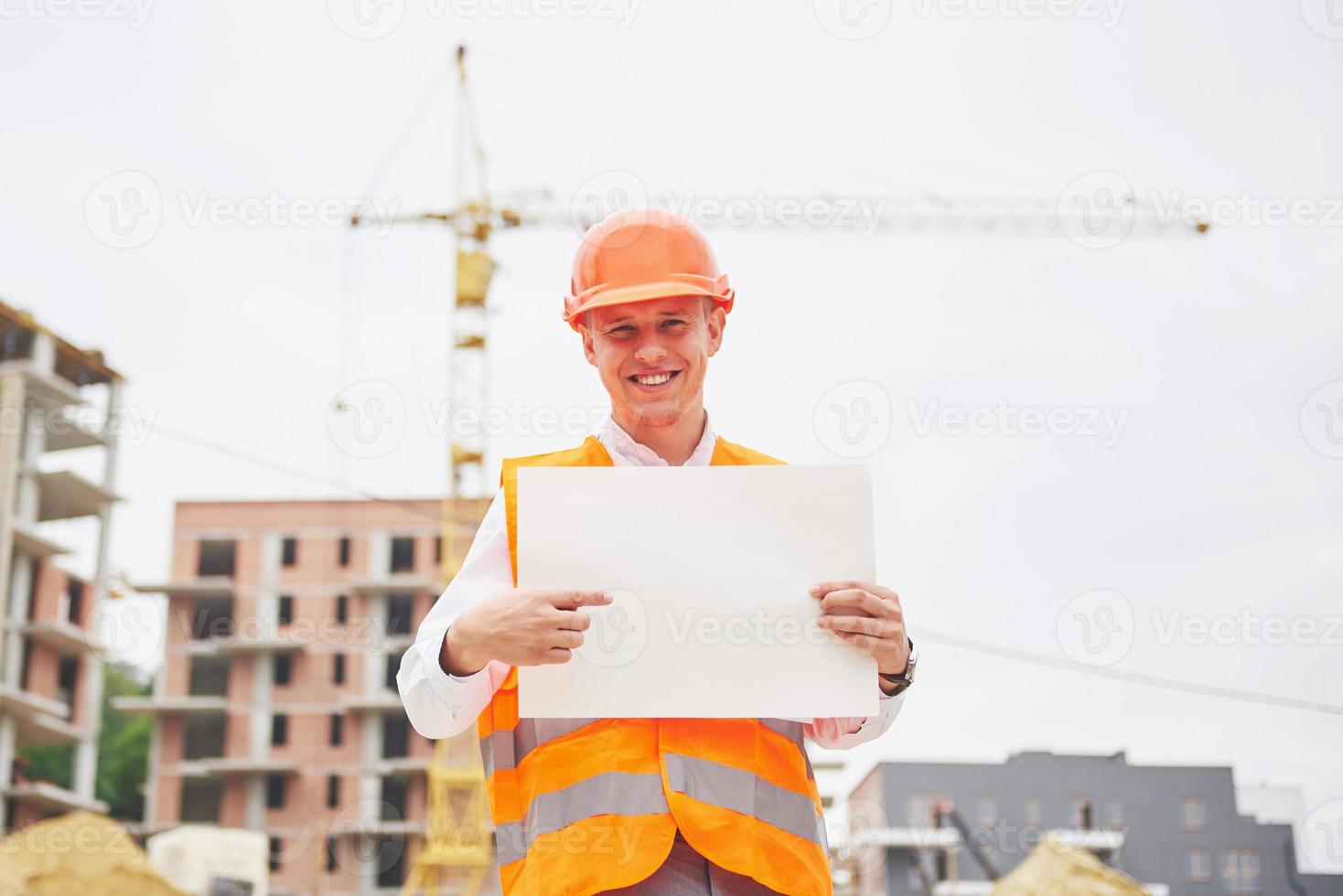 architecture and home renovation concept - man in helmet and gloves with blueprint in factory photo