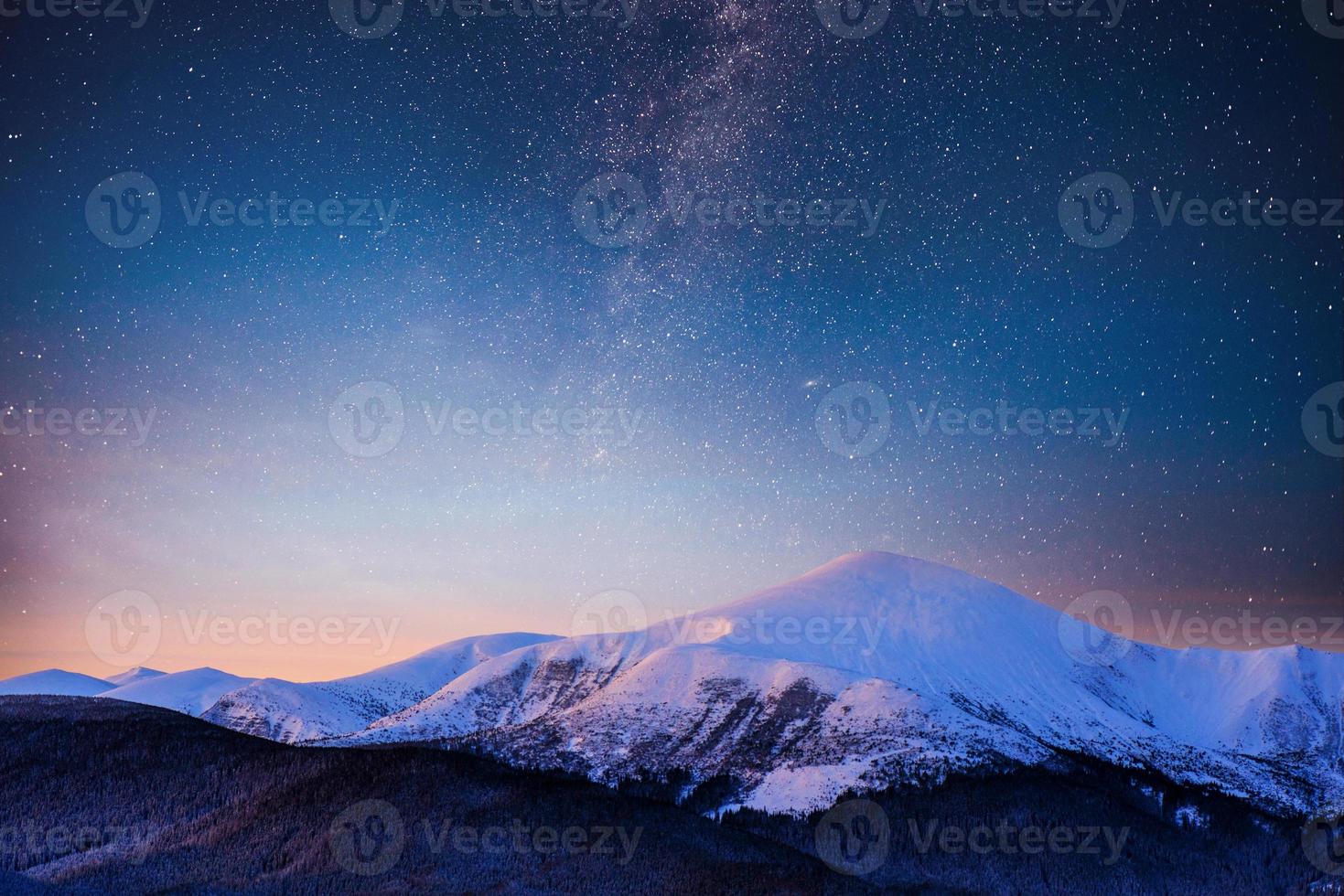 Beautiful winter landscape in the Carpathian mountains. Vibrant night sky with stars and nebula and galaxy. Deep sky astrophoto photo