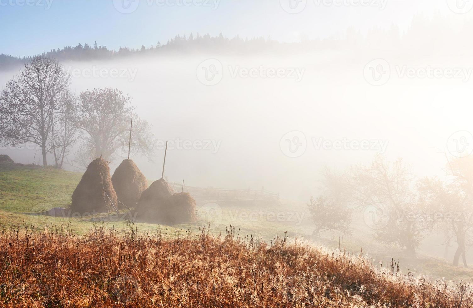 increíble paisaje montañoso con niebla y un pajar en otoño foto