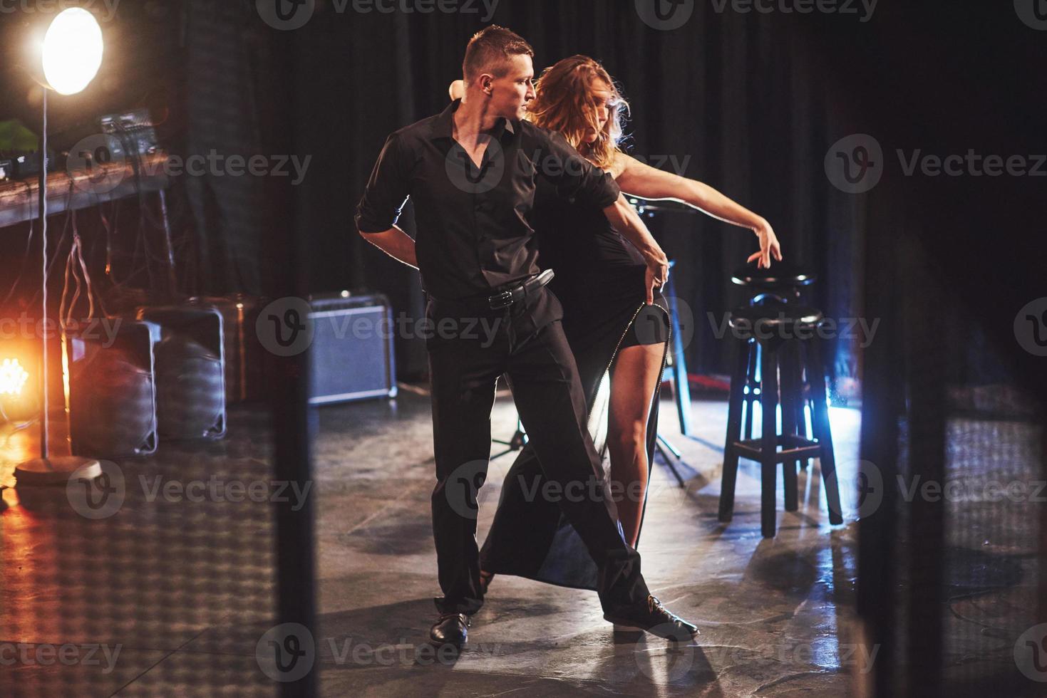 Skillful dancers performing in the dark room under the light photo