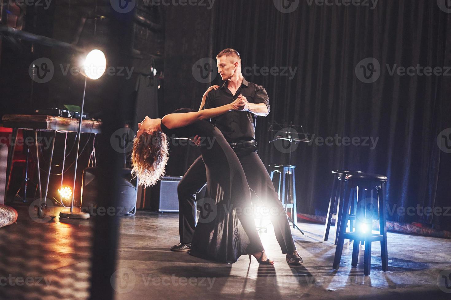Skillful dancers performing in the dark room under the light photo