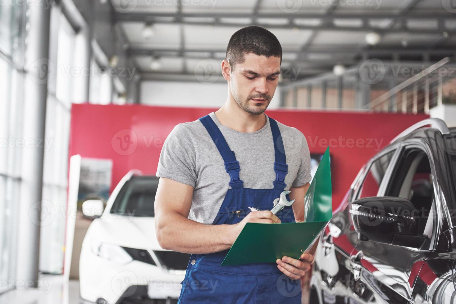 Portrait of a mechanic at work in his garage - car service, repair, maintenance and people concept photo