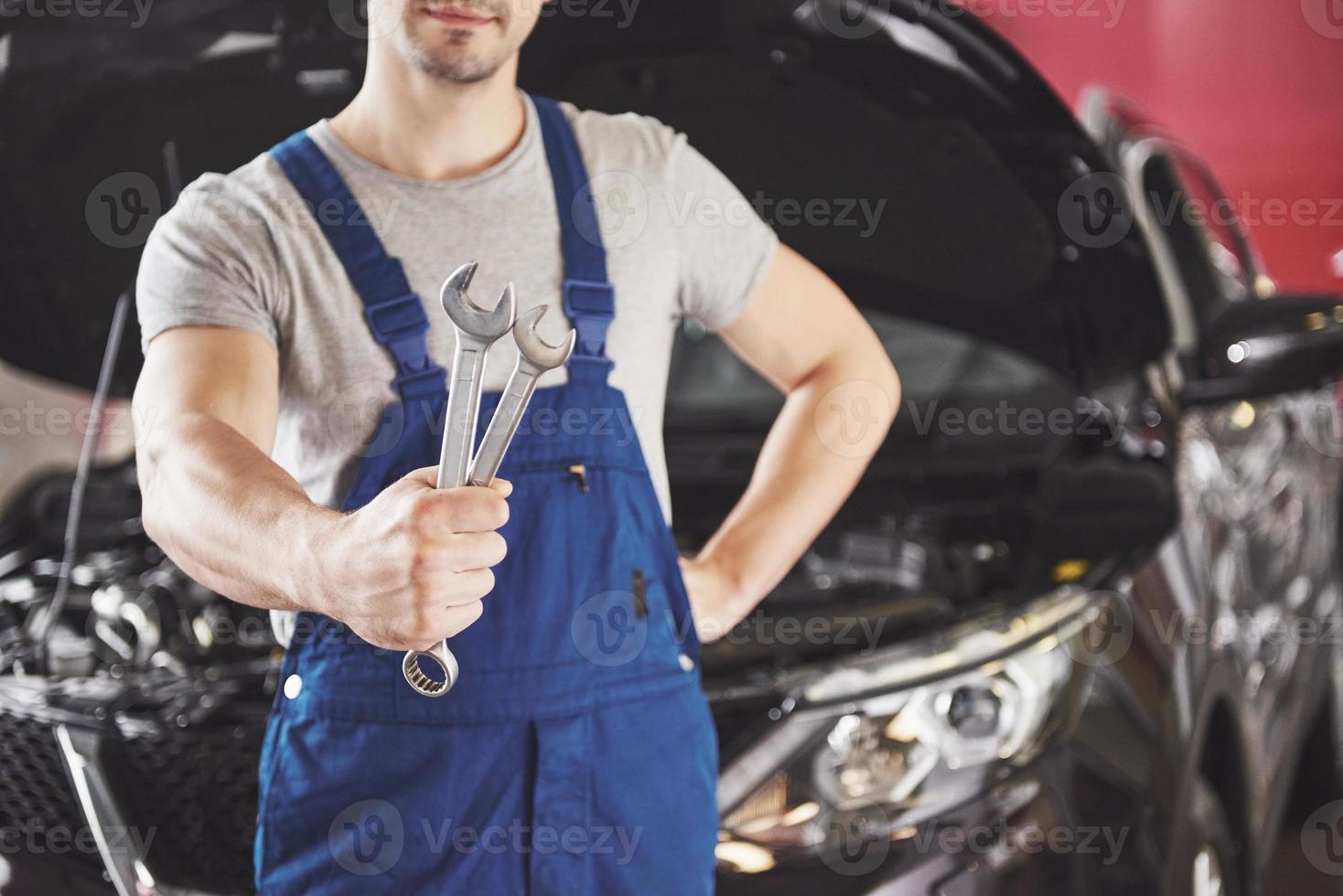 Hands of car mechanic with wrench in garage photo