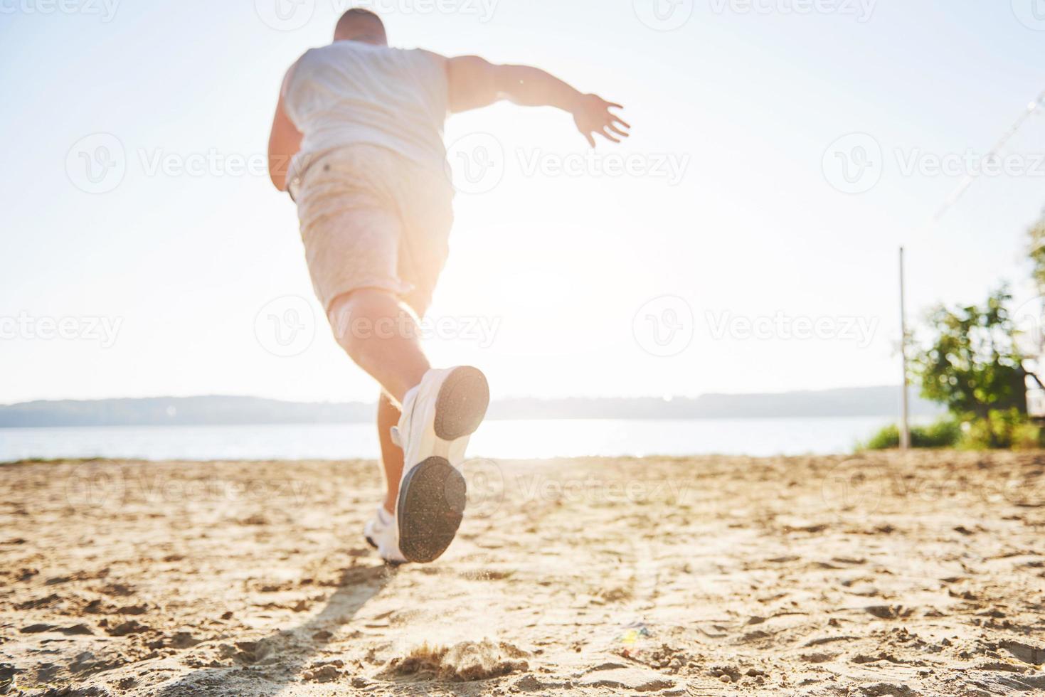 Outdoor cross-country running in summer sunshine concept for exercising, fitness and healthy lifestyle. Close up of feet of a man running in grass photo