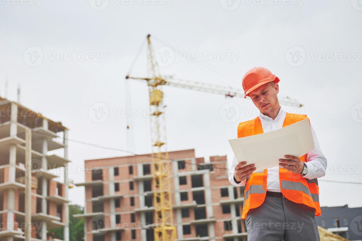 concepto de arquitectura y renovación del hogar - hombre con casco y guantes con plano en fábrica foto