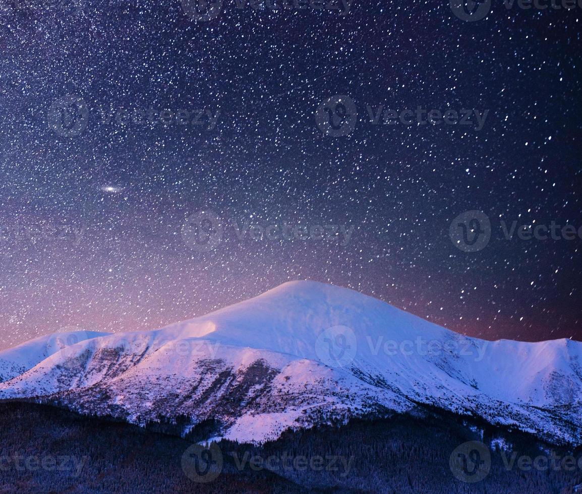 Beautiful winter landscape in the Carpathian mountains. Vibrant night sky with stars and nebula and galaxy. Deep sky astrophoto photo