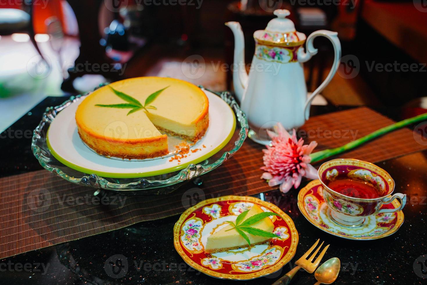 Cheesecake dessert pie, dairy recipe homemade on table. Delicious fresh peace of cake slice on plate. Tasty sweet food cannabis leaves on top. Morning gourmet plate closeup dish photography. photo