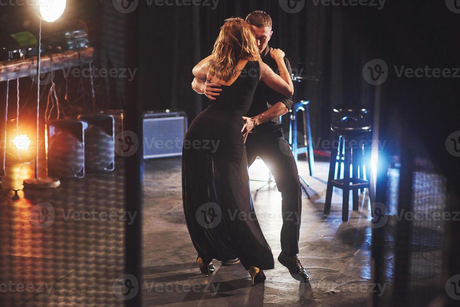 hábiles bailarines actuando en el cuarto oscuro bajo la luz foto