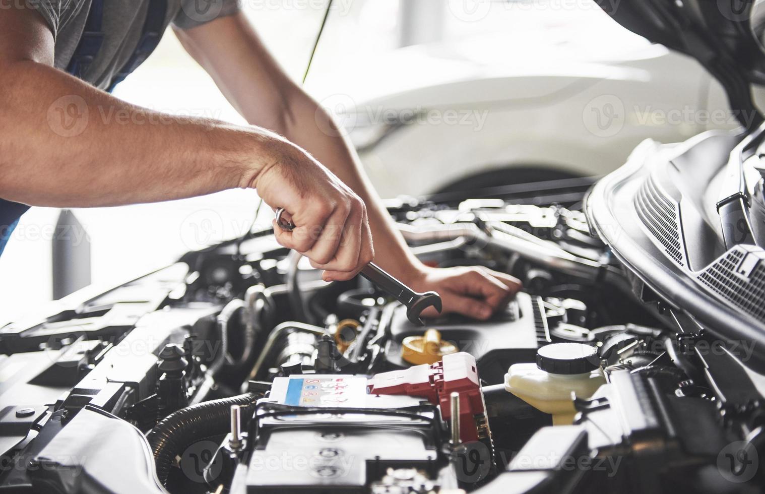 Imagen que muestra un trabajador de servicio de coche musculoso reparando el vehículo foto