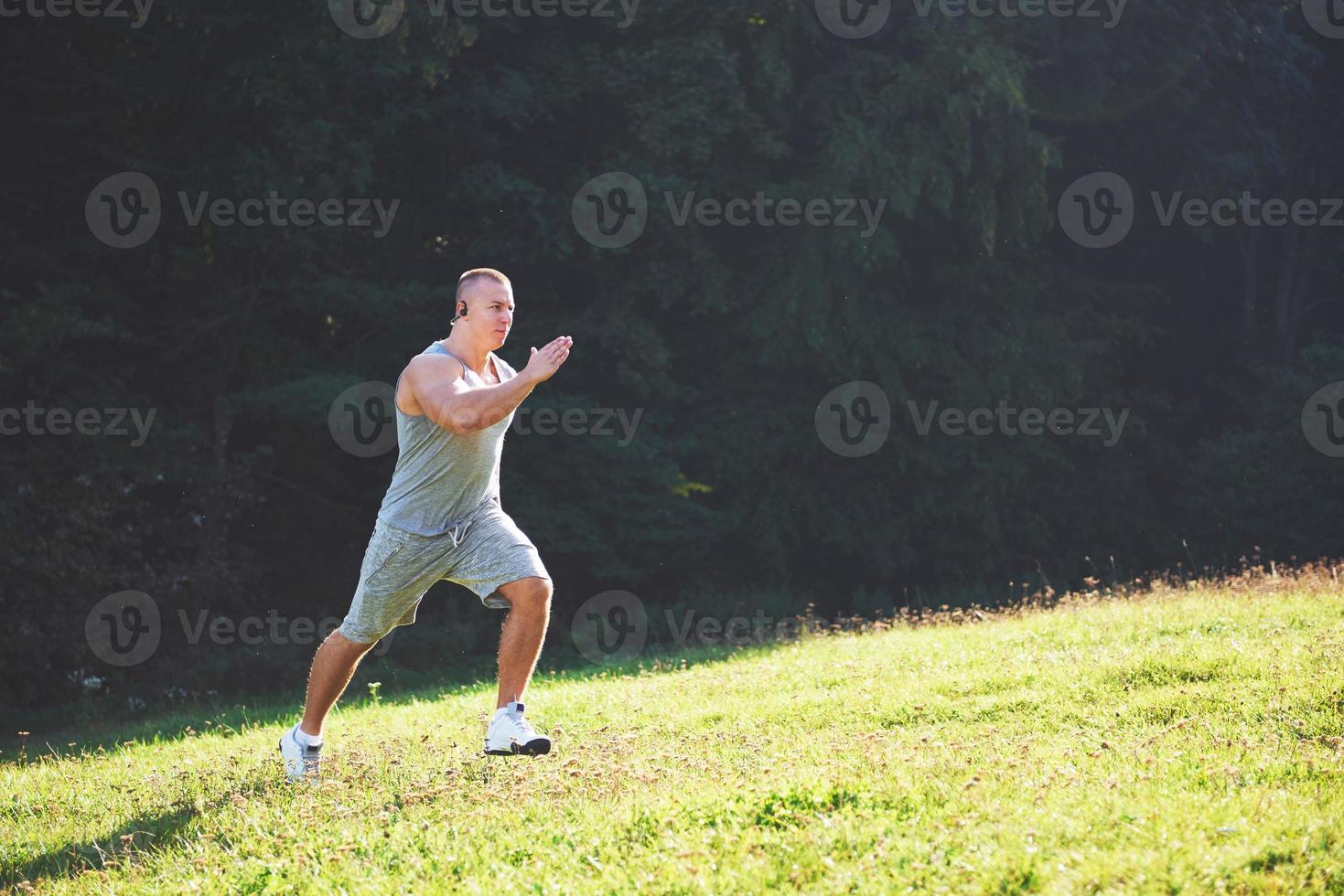 atleta fitness hombre trotando en la naturaleza durante la puesta de sol. persona corriendo ejercitándose viviendo un estilo de vida activo entrenando cardio en verano en ropa deportiva y zapatos. foto